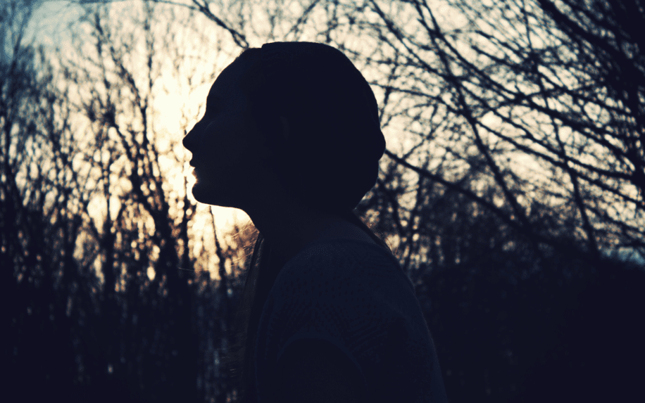 A silhouette of a woman in the woods.