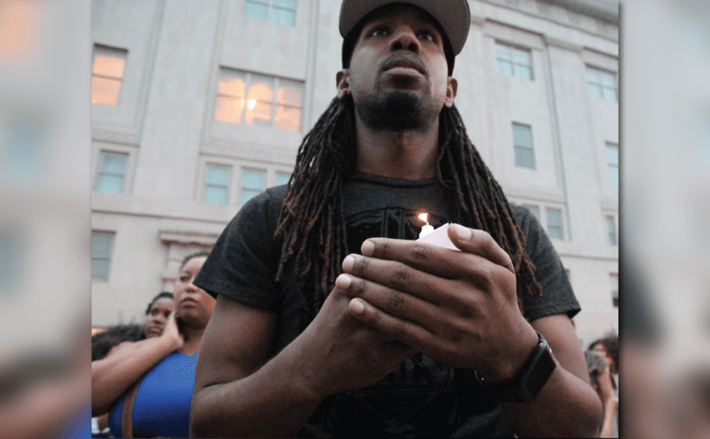 A man with dreadlocks holding a candle.