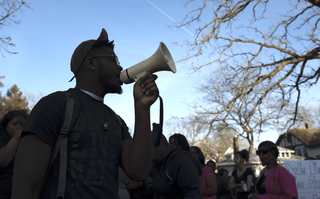 A man holding a megaphone in front of a group of people.