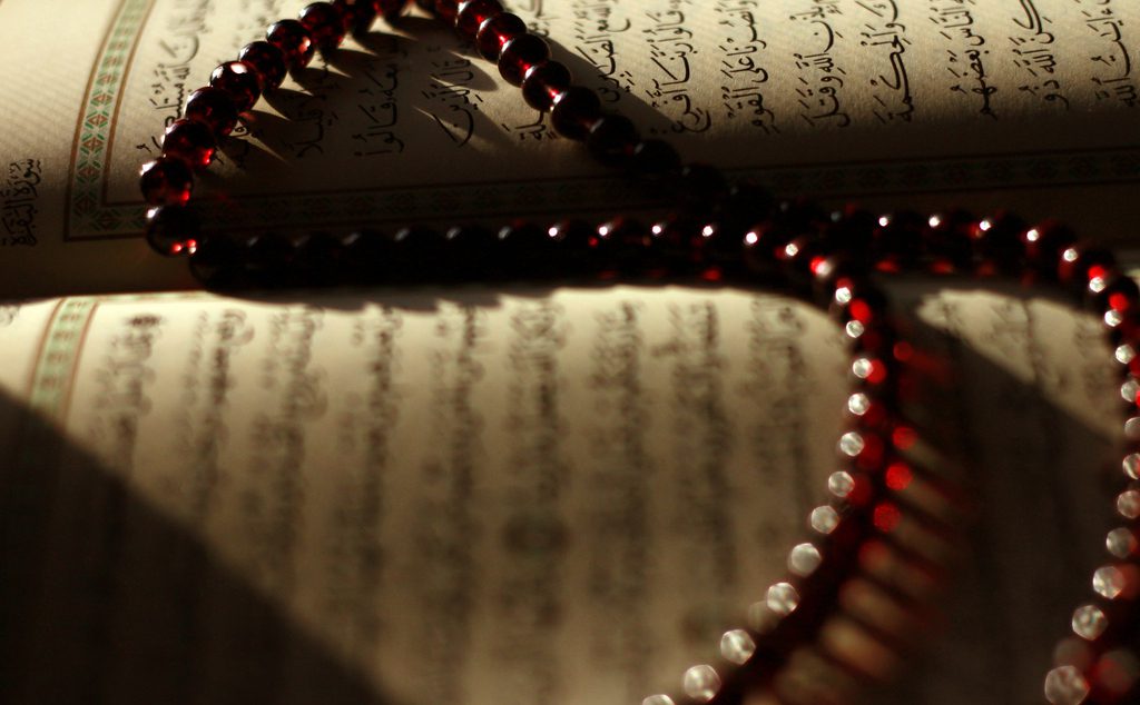 A red rosary sits on top of an open book.