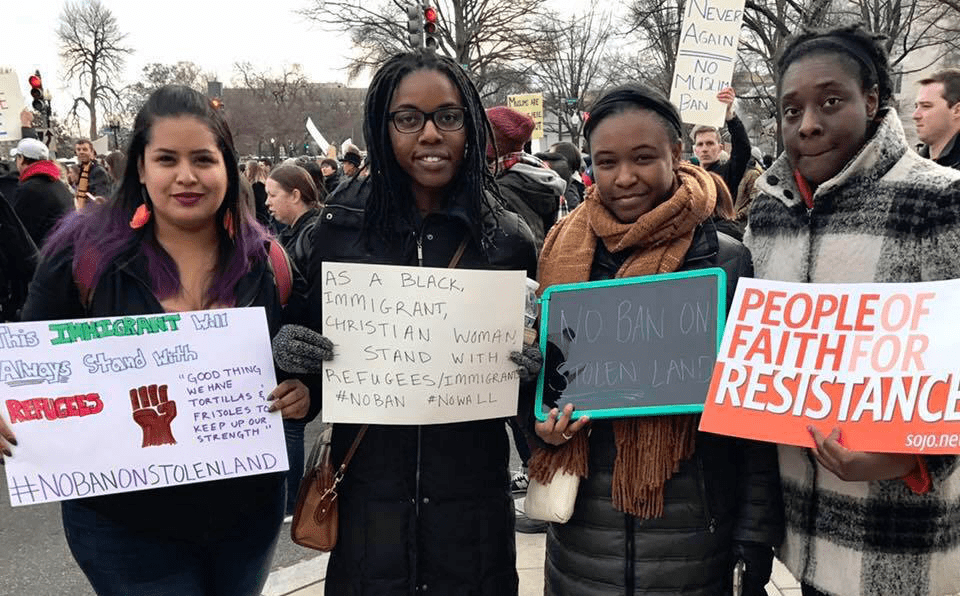 A group of people holding signs with the words people of faith for resistance.