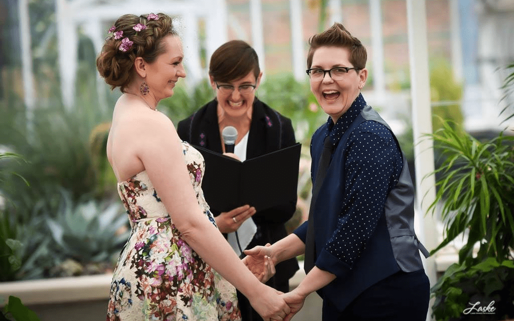 A bride and groom are getting married in a greenhouse.