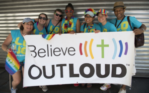 A group of people holding a sign that says believe out loud.
