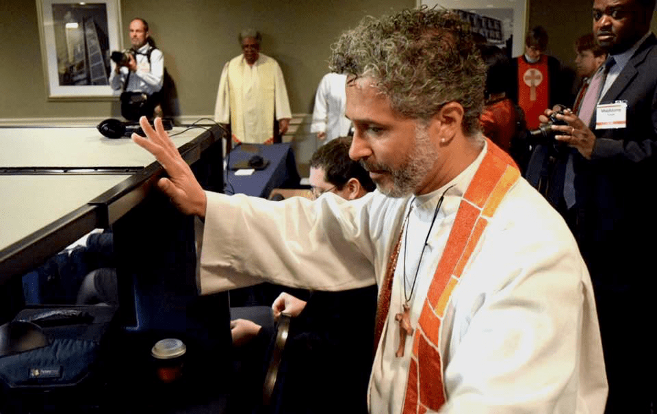 A priest is standing in front of a group of people.