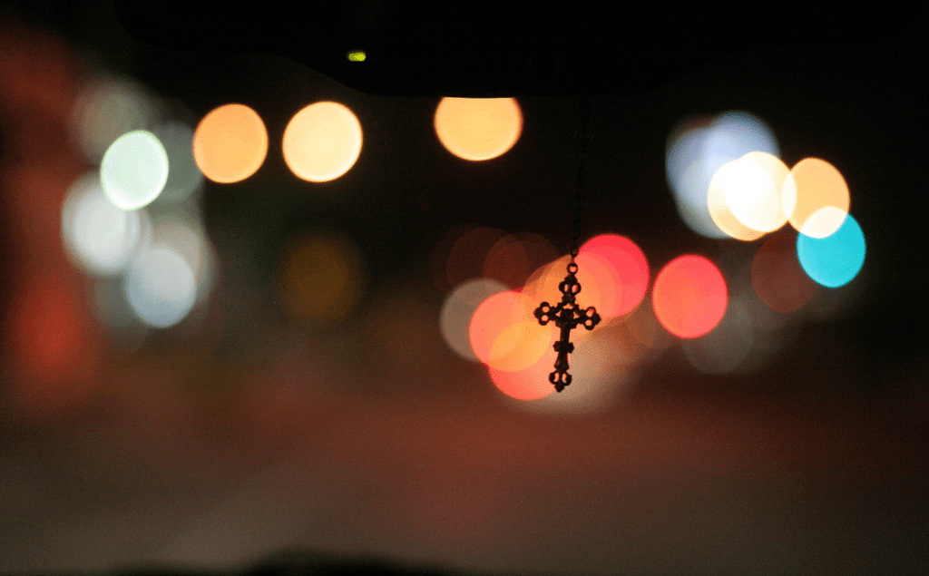 A cross hanging from the rearview mirror of a car.