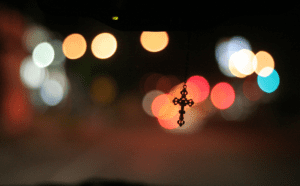 A cross hanging from the rearview mirror of a car.