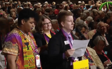 A group of people standing in front of a large crowd.