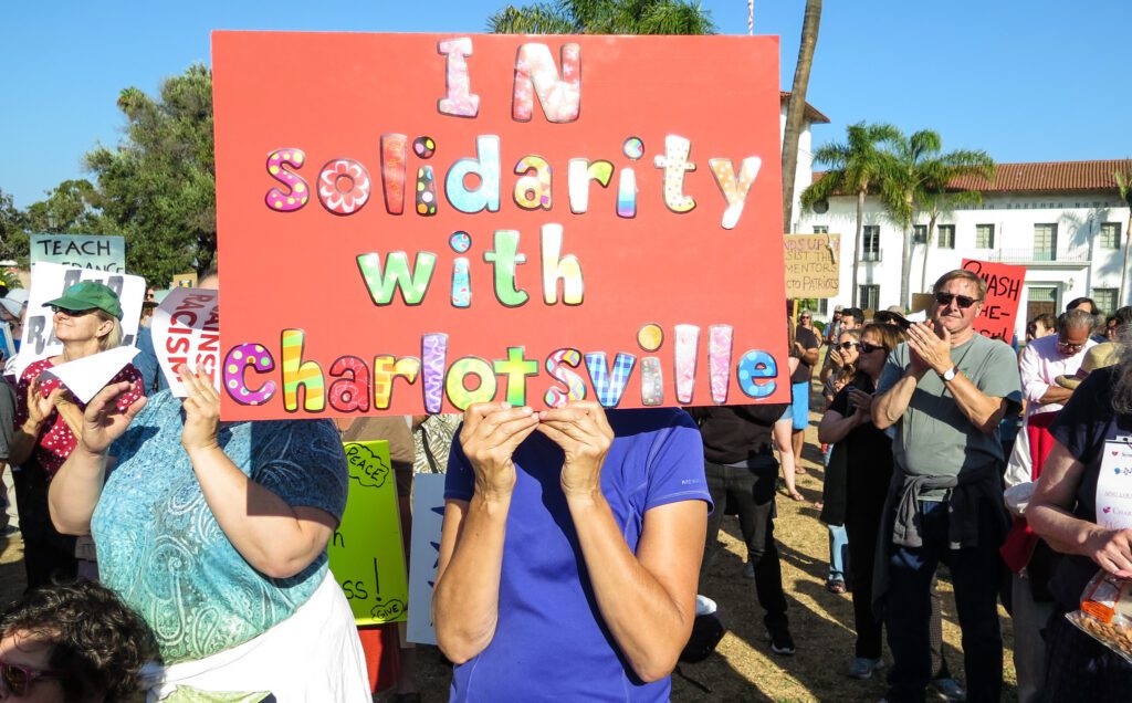 A woman holding up a sign that says solidarity with charlottesville.