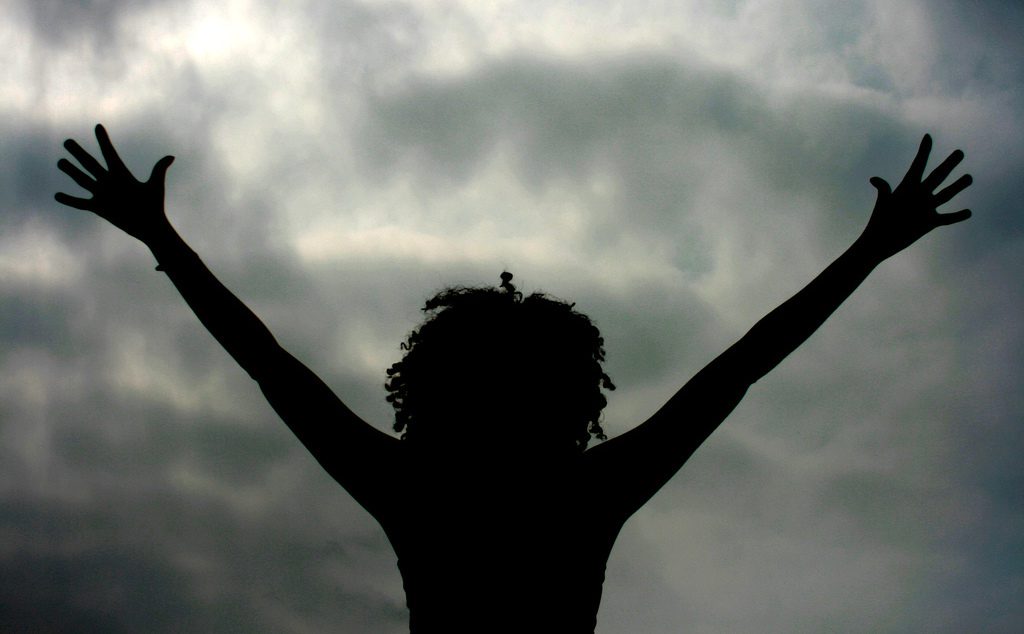 A silhouette of a woman with her arms raised in the air.