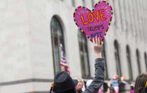 A woman holding up a sign that says love trump hate.