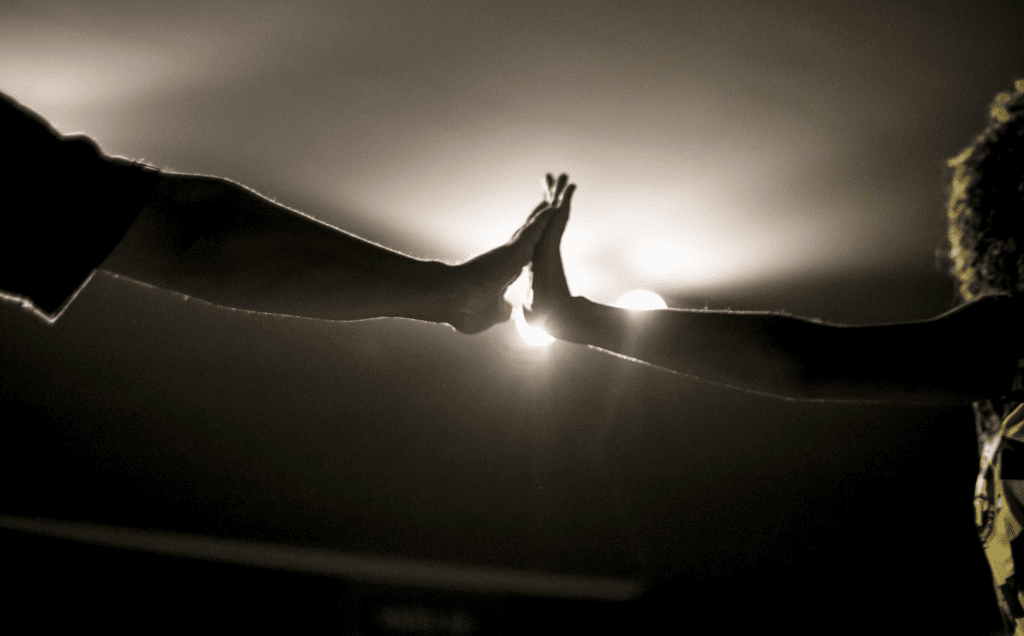 A black and white photo of two people giving each other a high five.