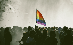 A group of people holding a rainbow flag in front of a fountain.