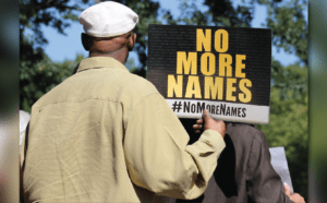 A man holding up a sign that says no more names.