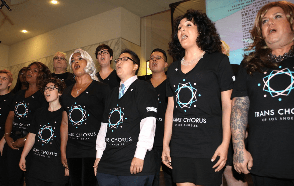 A group of people in black t - shirts singing in front of a screen.