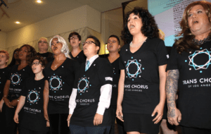 A group of people in black t - shirts singing in front of a screen.