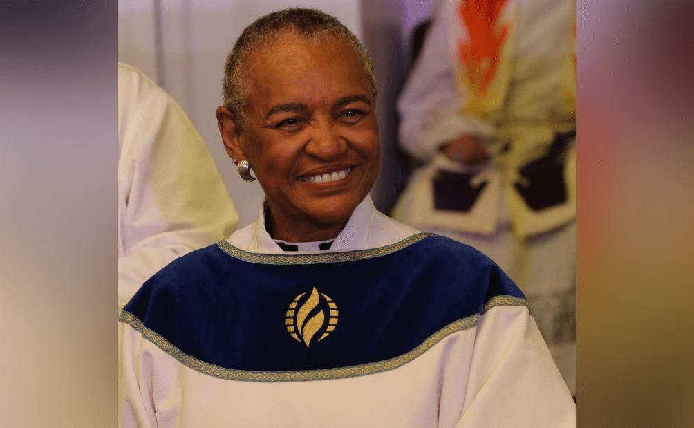 A woman in a white and blue robe is smiling.