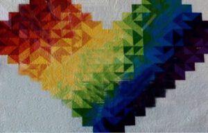 A quilt with a rainbow heart on it.
