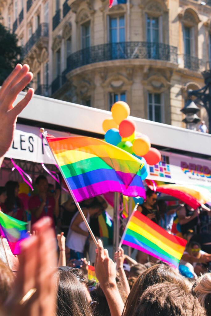 A group of people waving rainbow flags in front of a bus.