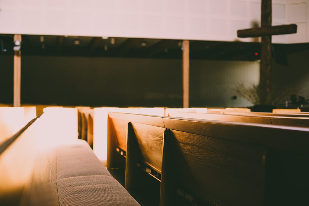 Empty church pews with a cross in the background.