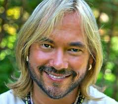 A man with long blonde hair smiling for the camera.