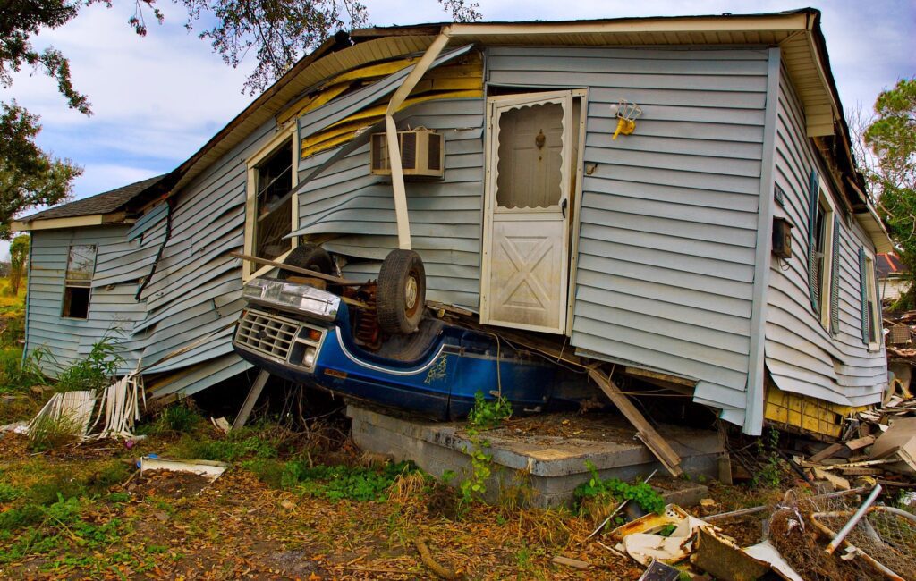 A blue car on top of a wrecked house.