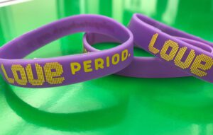 Three purple bracelets with the word love period on them.