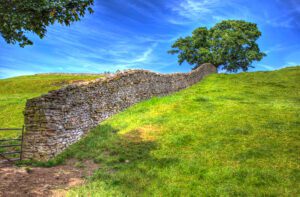 A stone wall next to a grassy hill.