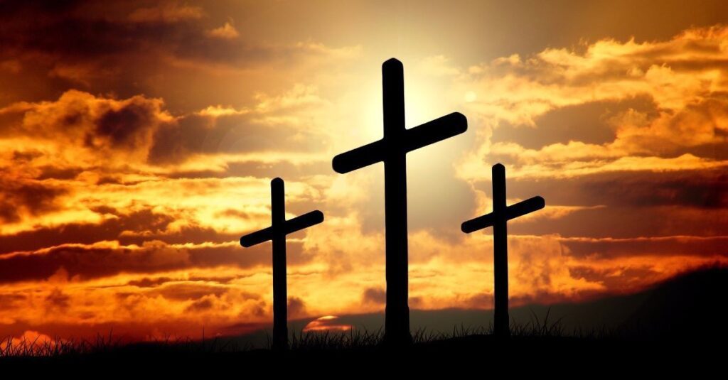 Three crosses are silhouetted against a sunset.