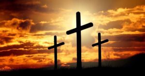 Three crosses are silhouetted against a sunset.