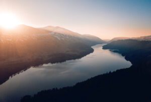 The sun is shining over a lake in the mountains.