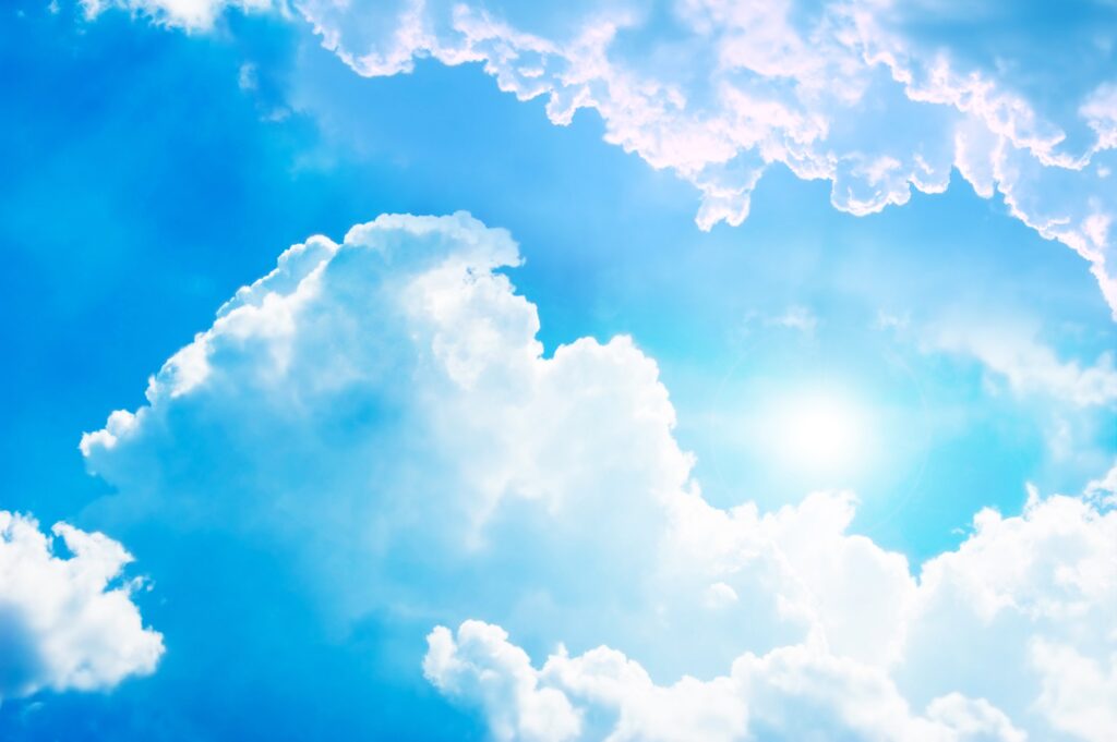 A blue sky with clouds and sun in the background.